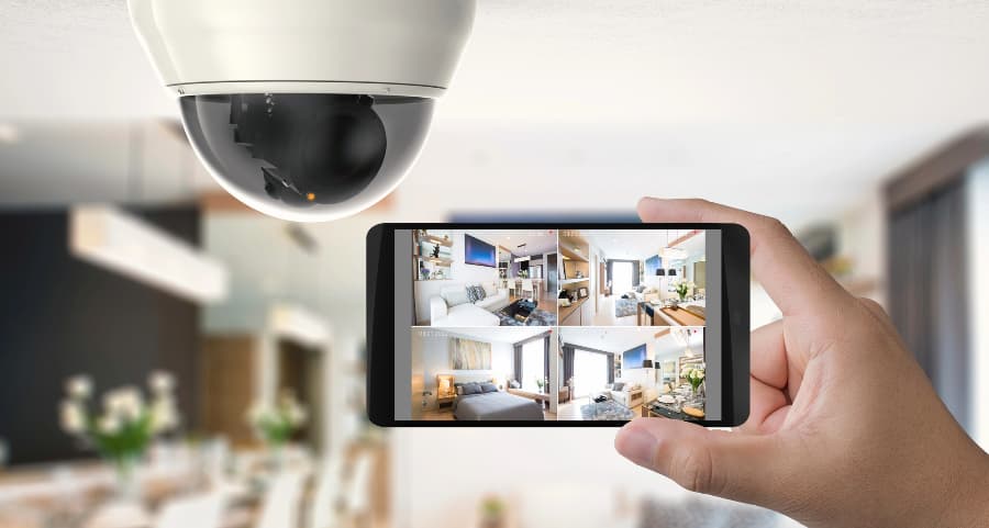 Homeowner holding smartphone with video feed from security cameras in 