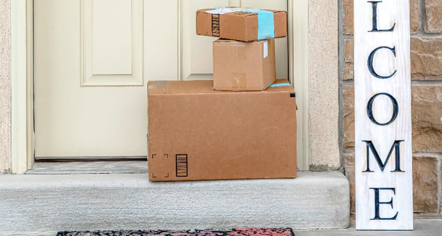 Packages on the doorstep of a home with a welcome sign in 